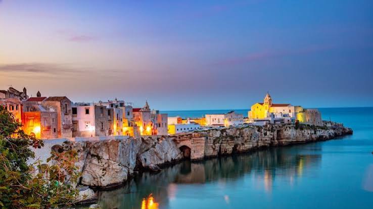 Vieste at dusk, the old town lit up on the cliffs above the sea